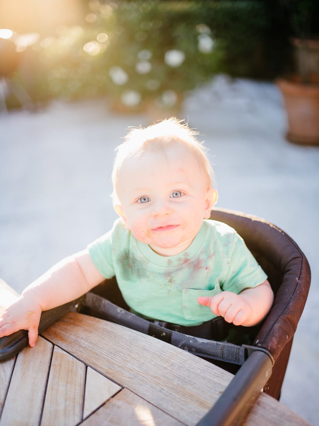 Messy baby sitting in his highchair outdoors - First Glimpse of France