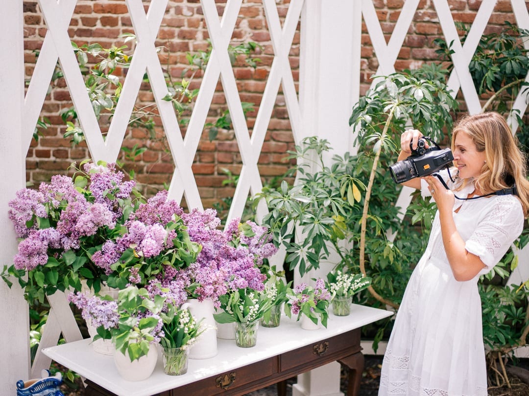 All Our Best Photography Tips & Tricks - Woman photographing flowers with a film camera